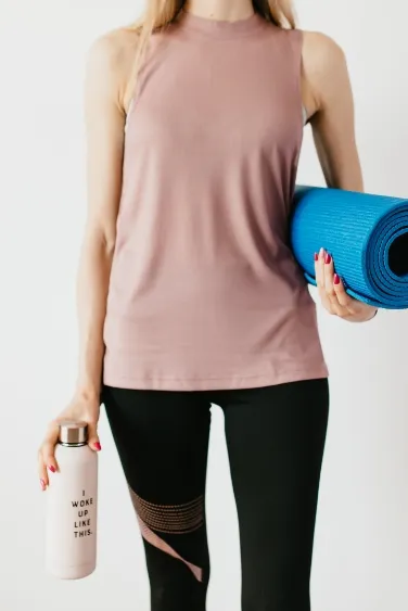 Žena v oblečení na cvičení a pomůckami k pilates tréninku.